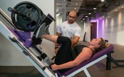 woman doing leg press with trainer