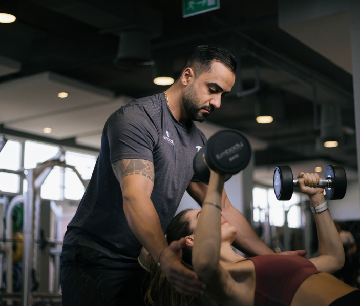 a male trainer trains a woman with dumbbells